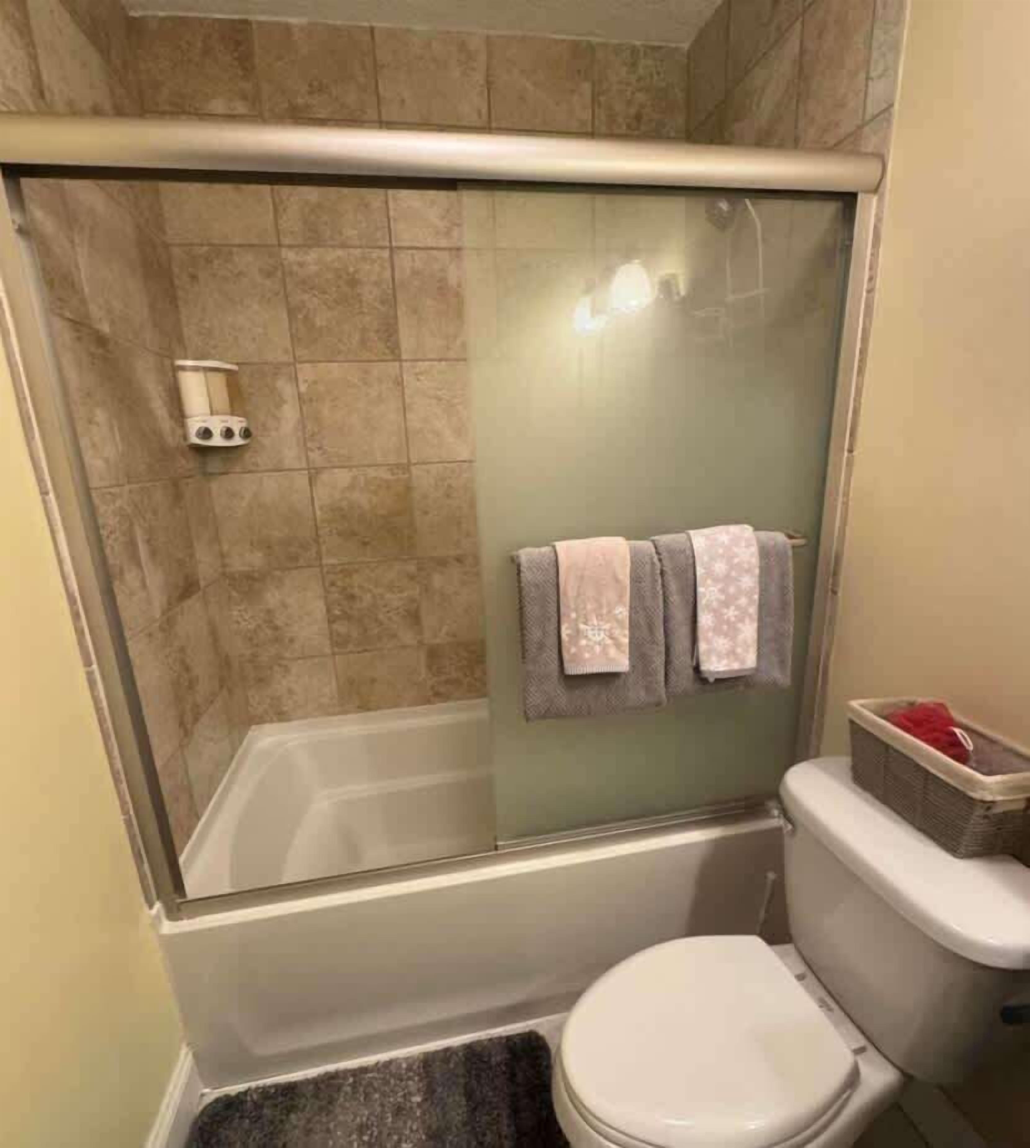 Ein Badezimmer mit Duschkabine, Toilette und einem kleinen Mülleimer.