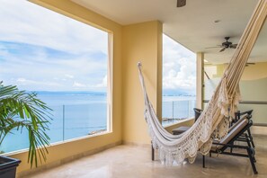 Ein Hängesessel auf einem Balkon mit Blick auf das Meer.