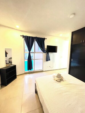 A hotel room with a bed, a TV mounted on the wall, a wardrobe, and a window with curtains. - Dreams Lagoon (Cancún)