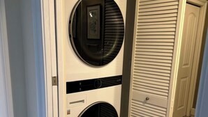 Lavadora y secadora compactas, empotradas en una pared, en un pasillo con puerta que da a otra habitación.