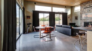 Una habitación amplia con una gran mesa de comedor, sillas modernas, un sofá y una chimenea de piedra.