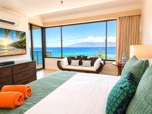 A hotel room with a large window, a bed, a sofa, a TV, and a dresser. - Sands Of Kahana Oceanfront 3-Bedroom Penthouse | Car Incl w/ 6 nights | SOK-381 by KBM (Lahaina)