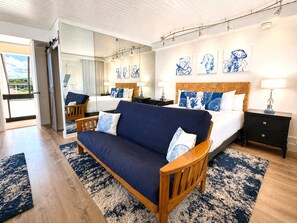 Ein Hotelzimmer mit Sofa, Bett, Nachttisch, Spiegel und Bildern an der Wand.