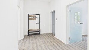 Um corredor com um porta-roupas, uma porta e um interruptor de luz na parede.