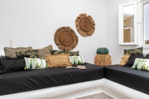 Ein modernes Wohnzimmer mit einem schwarzen Sofa, dekorativen Wandbehängen und einem großen Fenster.