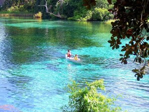 A clear river with a boat carrying two people.