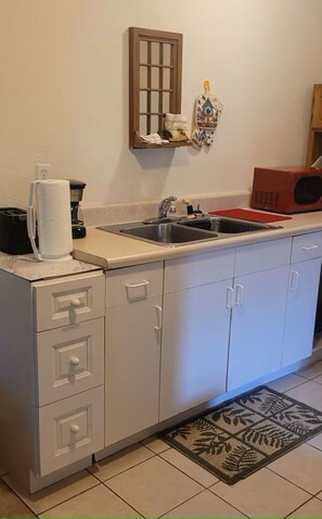 A kitchen with a sink, a coffee maker, a toaster, and a microwave.