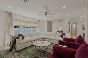 Ein Wohnzimmer mit einem Ecksofa, einem Couchtisch und einem roten Sessel.