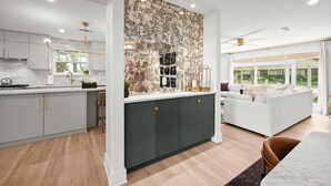 Una cocina moderna con una isla central, muebles oscuros y un amplio ventanal con vistas a un jardín.