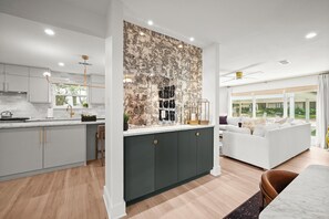 Una cocina moderna con una isla central, muebles oscuros y un amplio ventanal con vistas a un jardín.
