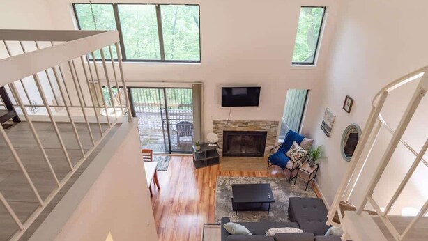 Un vaste espace de vie doté d’une cheminée, d’un téléviseur et d’un balcon aménagé avec du mobilier d’extérieur.