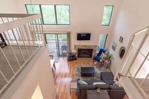 A spacious living area with a fireplace, a television, and a balcony with outdoor furniture.
