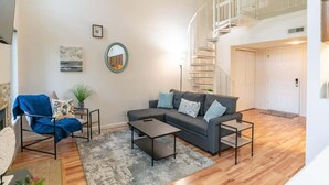 Un salon moderne avec un canapé, une table basse et un escalier.