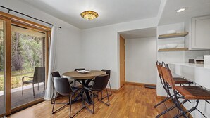 Eine moderne Küche mit weißen Schränken, ein Essbereich mit rundem Tisch und Stühlen sowie eine Glastür, die auf einen Balkon führt.