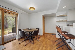 A modern kitchen with white cabinets, a dining area with a round table and chairs, and a sliding glass door leading to a balcony. - Riverfront Ski & Fish Condo, Near BC & Vail (Edwards)