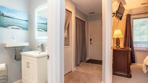 A hotel room with a bathroom, a hallway, and a bed. - Woodland Escape Condo (Bloomington)