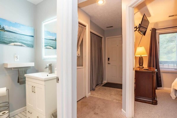 A hotel room with a bathroom, a hallway, and a bed.
