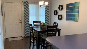 A dining area with a table, chairs, a chandelier, and a kitchen counter.