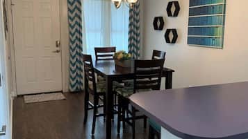 Un espace repas comprenant une table, des chaises, un lustre et un comptoir de cuisine.