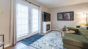A living room with a fireplace, a sofa, a coffee table, and a TV. - Convenient Wayfarer’s Rest (Bloomington)