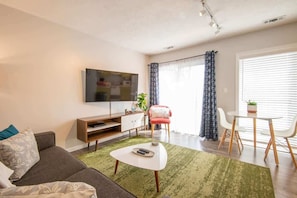 Un salon moderne comprenant un canapé, une table basse, un téléviseur et un coin repas avec des chaises et une table.