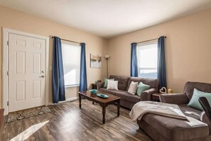Un salon avec un canapé marron, une table basse et une porte.