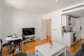 Ein modernes Wohnzimmer mit Essbereich, einem Fernseher und einer Küche.