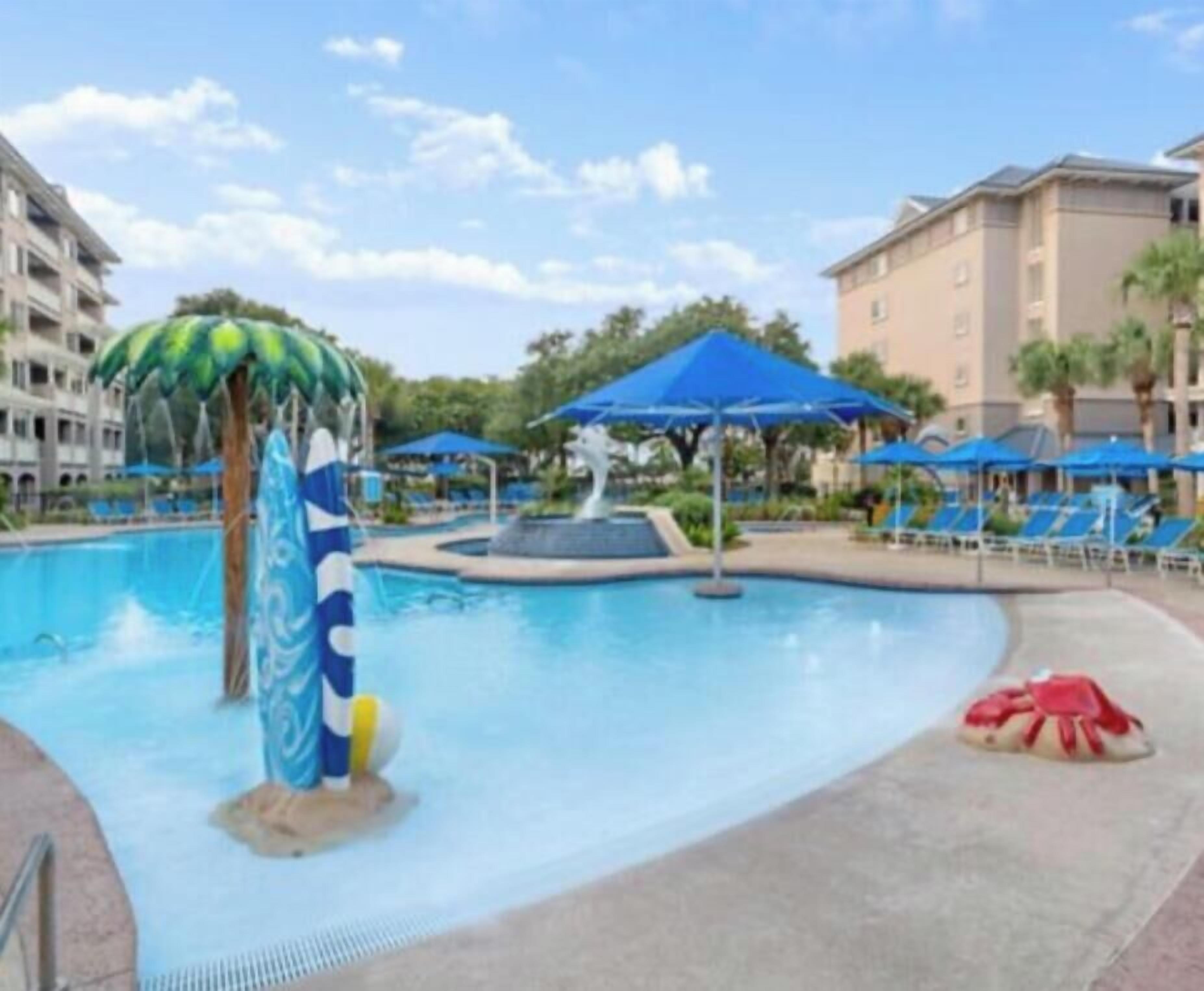 Une piscine avec un toboggan, des chaises longues et des parasols.