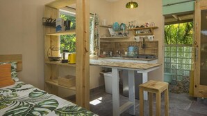 Habitación compacta con cama, una mesita, kitchenette y ventana con vistas a zonas verdes.