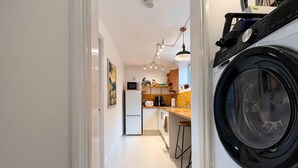 A narrow hallway leading to a kitchen with a washing machine, a refrigerator, and a microwave. - Stylish and peaceful 2 bedroom / 2 bathroom Oasis with a private Sun Courtyard (Saxmundham)