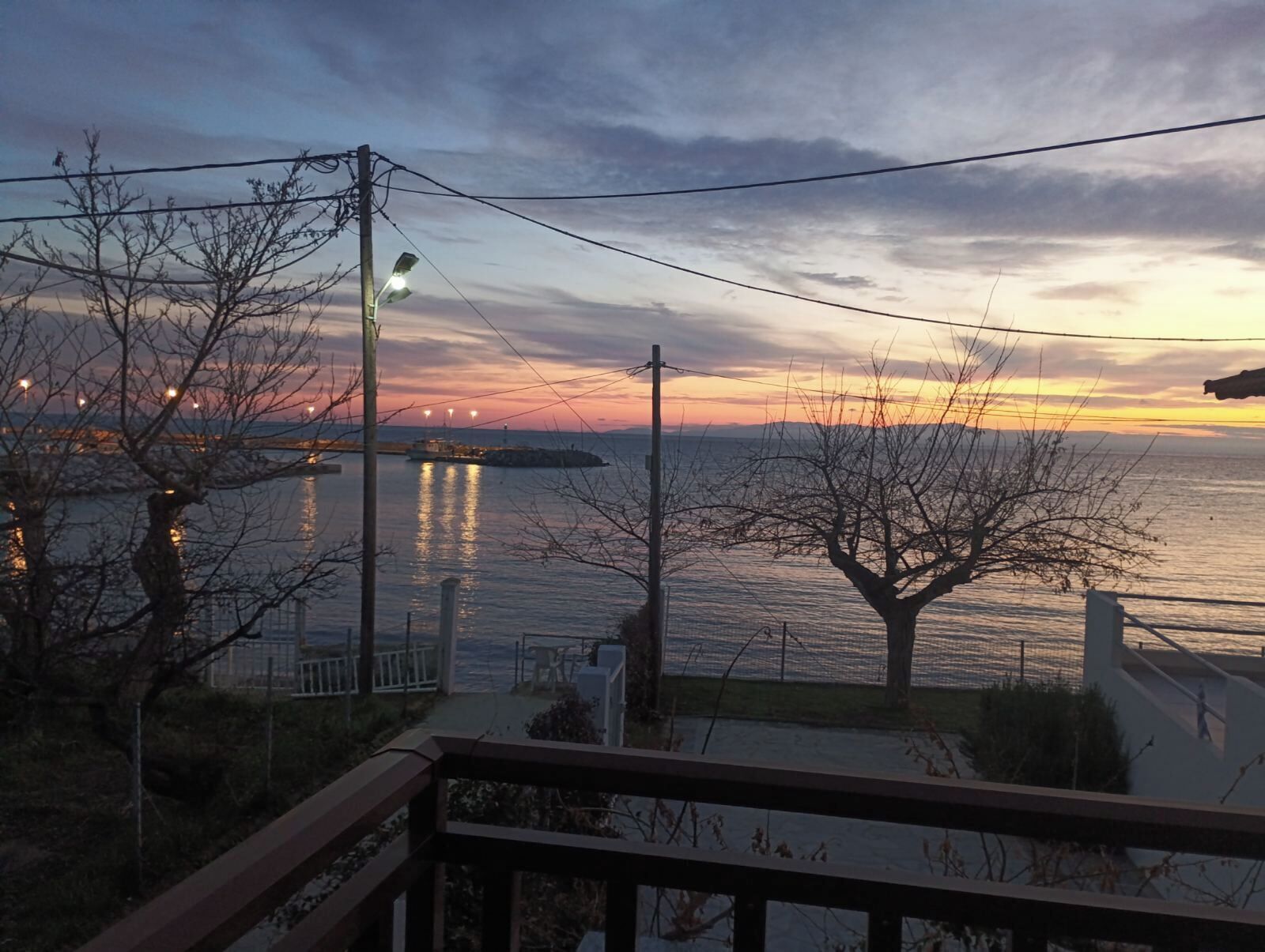 Une vue sur le bord de l’eau, avec un pont, des arbres sans feuilles et une rambarde.