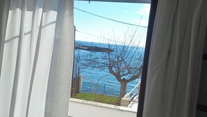 Habitación con vista al mar a través de una ventana con cortinas blancas.