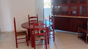 Un comedor con una mesa redonda y sillas, un ventilador de techo y vistas al exterior.