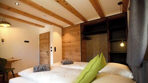 Een slaapkamer met twee bedden, houten balken in het plafond, een bureau en een stoel.