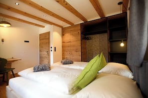Ein Schlafzimmer mit zwei Betten, Holzbalken an der Decke, einem Schreibtisch und einem Stuhl.