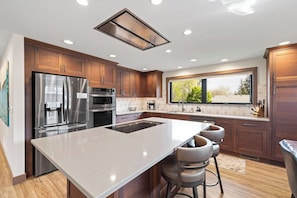 A modern kitchen with a large island, stainless steel appliances, and a window providing a view. - Lime Creek Retreat - Central Downtown (Rapid City)