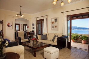 Ein Wohnzimmer mit einer Couch, Sesseln, einem Couchtisch und Meerblick.