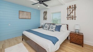 A bedroom with a bed, a ceiling fan, a nightstand, and wall decorations.