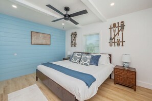 A bedroom with a bed, a ceiling fan, a nightstand, and wall decorations.