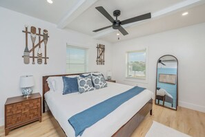 A bedroom with a bed, a nightstand, a dresser, a ceiling fan, and a mirror.
