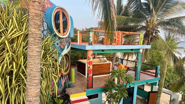 A multi-level structure with a colorful exterior, a wooden window, and a pool area.