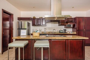 A modern kitchen with granite countertops, stainless steel appliances, and dark wood cabinetry. - 3-bedroom villa in beautiful Quepos with AC for relaxing stays (Quepos)