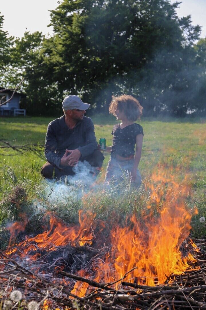 Zwei Personen in einer Outdoor-Umgebung am Lagerfeuer.