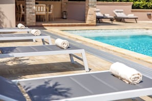 Ein Poolbereich mit Liegestühlen und Handtüchern.