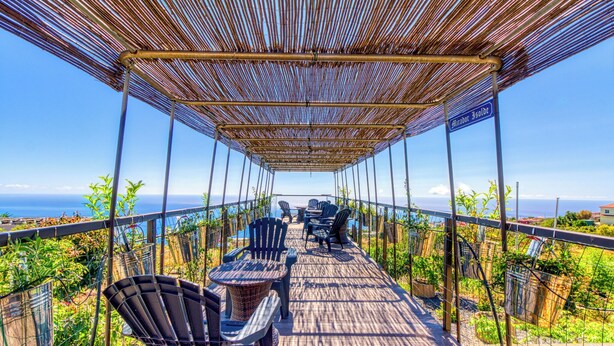 Un espacio de estar al aire libre techado, con sillas y mesas, con vistas panorámicas.