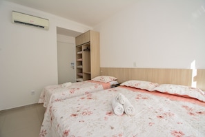 A hotel room with two beds, a wardrobe, and an air conditioning unit. - Refúgio nos Ingleses a 200m da praia  (Florianópolis)