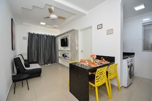 A modern living space with a dining area, a sofa, a TV, and a washing machine. - Refúgio nos Ingleses a 200m da praia  (Florianópolis)