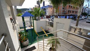 A balcony with a metal railing, a children's play area with a slide, and a potted plant.