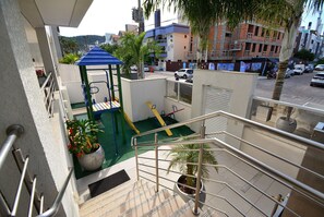 A balcony with a metal railing, a children's play area with a slide, and a potted plant. - Refúgio nos Ingleses a 200m da praia  (Florianópolis)