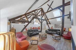 Ein Innenraum mit freiliegenden Holzbalken, Ledersofas und einem modernen Couchtisch.